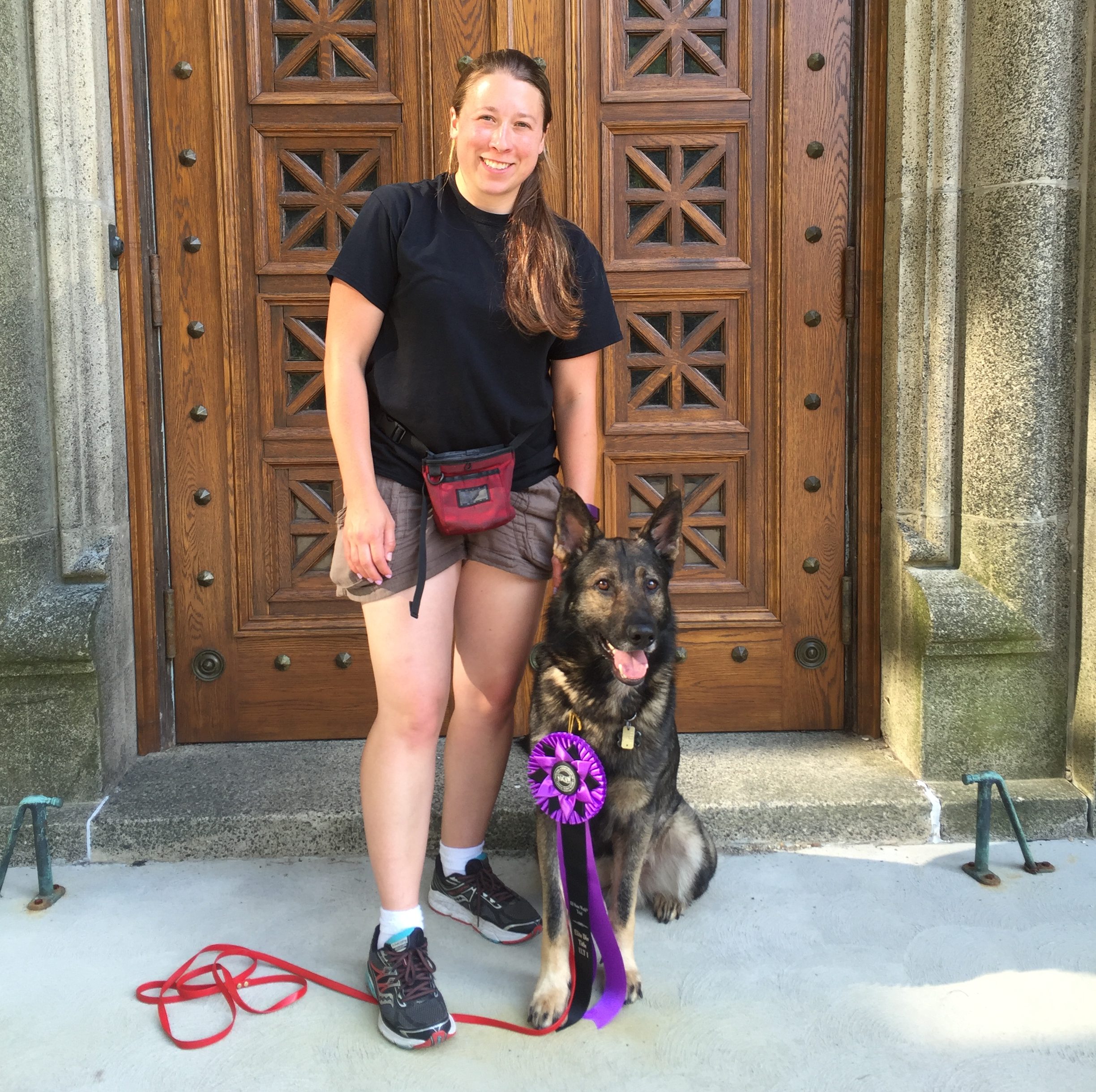 Dog sitting at heel wearing large ribbon award