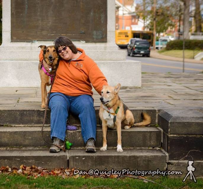 woman sitting on steps with a dog standing on either dise